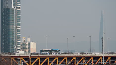 el tráfico en el puente de seongsu, la torre mundial de lotte en el fondo, a través de la niebla