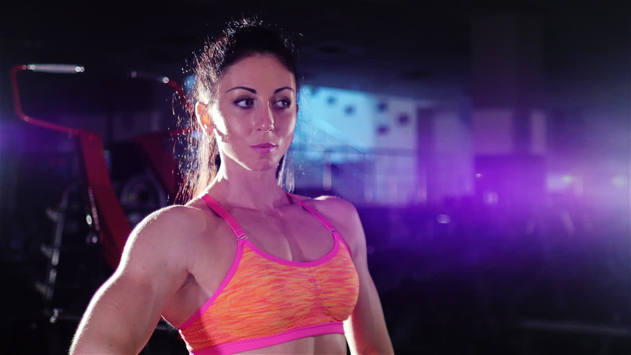 Athletische Frau, eine professionelle Bodybuilderin, posiert vor einem Spiegel und zeigt ihre Muskeln.