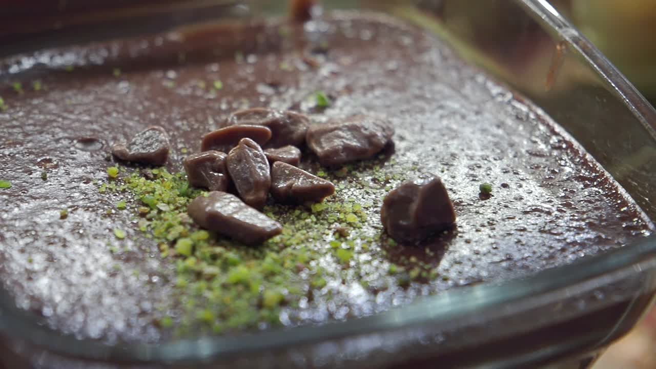 Nærbilde av sjokoladepudding pyntet med pistasj og sjokolade
