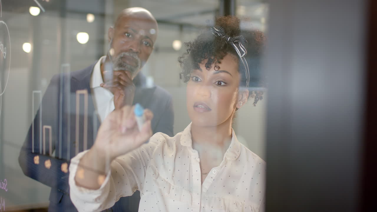 Vertical video of diverse business people by glass wall in office with copy space