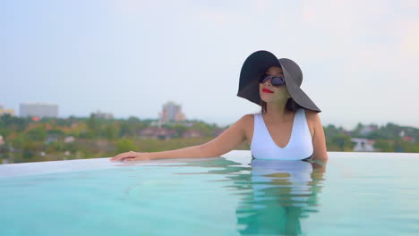 Atractiva-Mujer-Asiática-Disfrutando-De-Sus-Vacaciones-De-Verano-En-La-Piscina-Con-Una-Vista-Increíble-De-La-Ciudad-Tropical