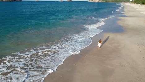 woman walking on a beautiful sandy beach with clear turquoise water