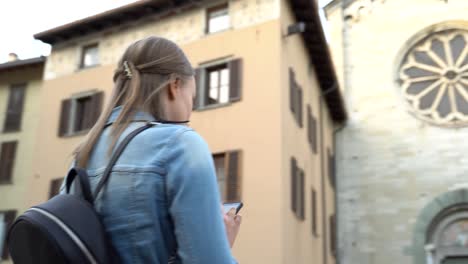 female tourist in the old city with mobile phone. camera is flying around.