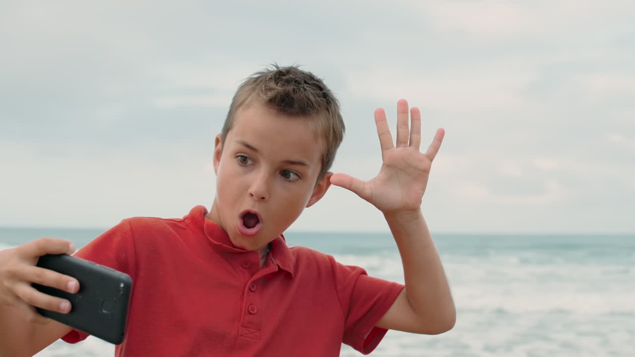 un chico concentrado tomando una selfie en su teléfono inteligente en la playa. un chico relajándose en la playa.
