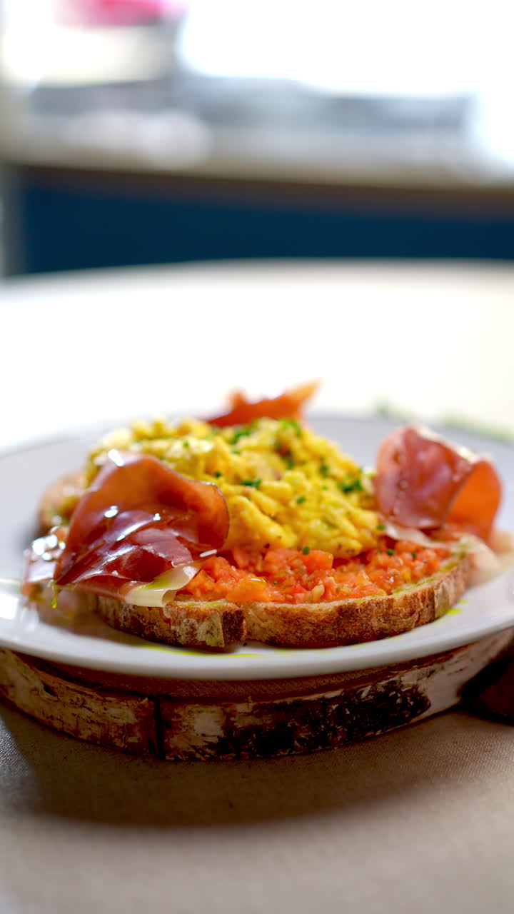 Eastern European cuisine presents scrambled eggs with grated carrots and ham on a slice of toasted bread, served on a white plate and wooden support, isolated on a white background