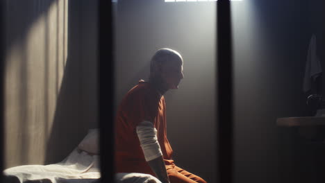 stressed inmate walking anxiously around prison cell, then sitting on bed