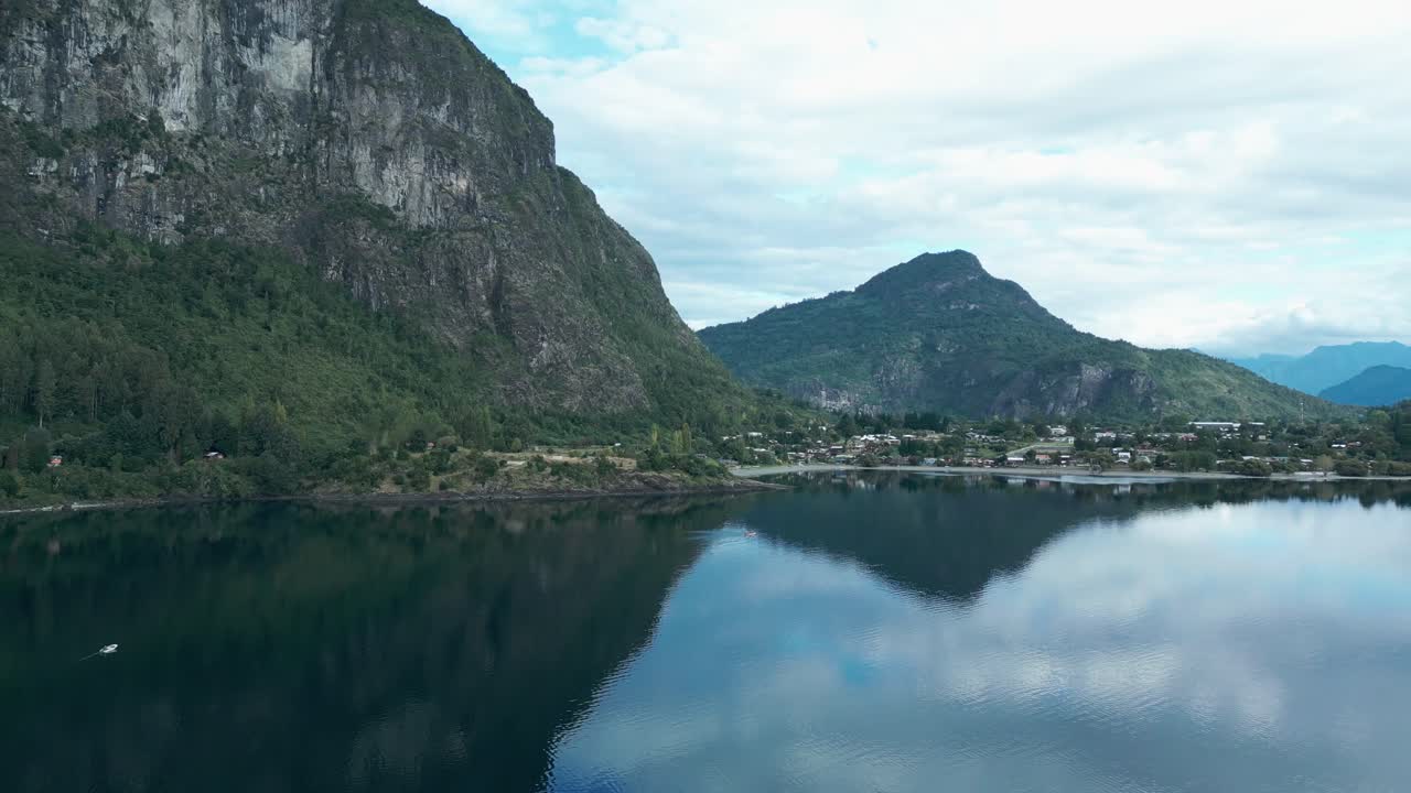 Panning drone aerial of Llifen on Ranco Lake with dramatic rocky cliffs, mountains backdrop, reflections, and Chilean wilderness