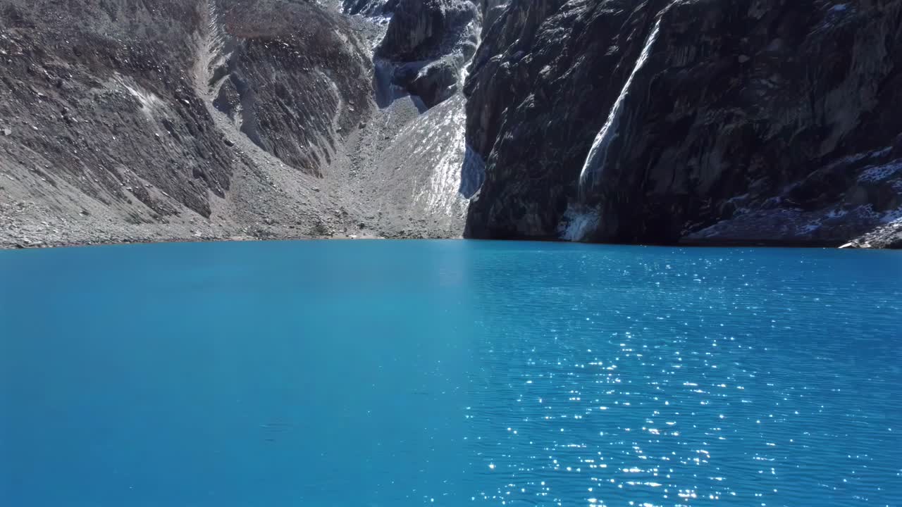 Aerial of Laguna 69 striking blue waters set against the dramatic Andes Mountains