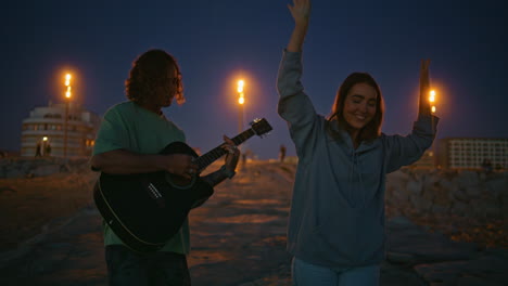 carefree woman enjoying music dancing evening beach. romantic man playing guitar