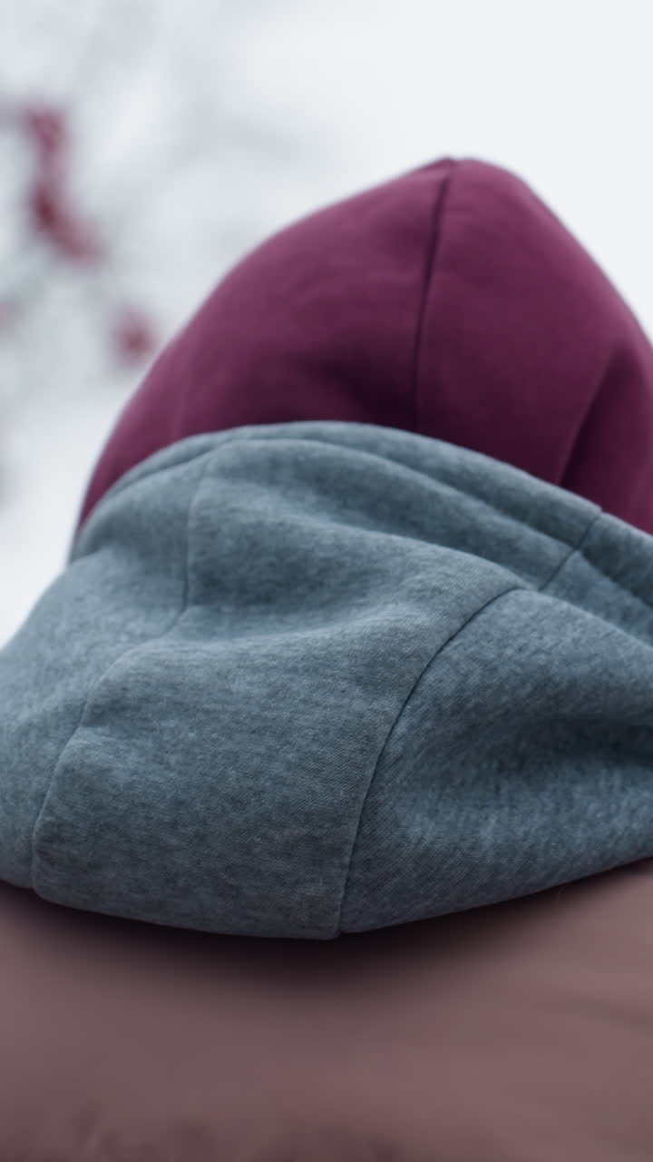 따뜻한 겨울 옷을 입은 사람이 추운 날씨에 고있는 뒷면, 후드 재과 베니는 추운 환경에 대한 따뜻함을 제공합니다, 겨울 잎자루와 함께 흐릿한 나무 가지