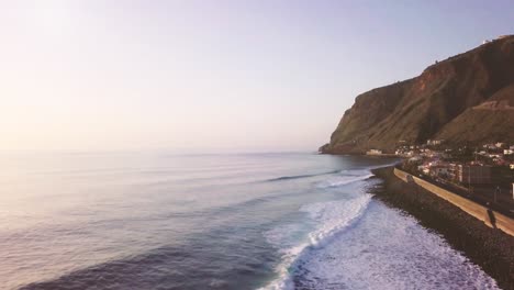 Toma-Aérea-Del-Pueblo-De-Pescadores-De-La-Costa-Con-Olas-En-Paul-Do-Mar-En-La-Isla-De-Madeira-Al-Atardecer