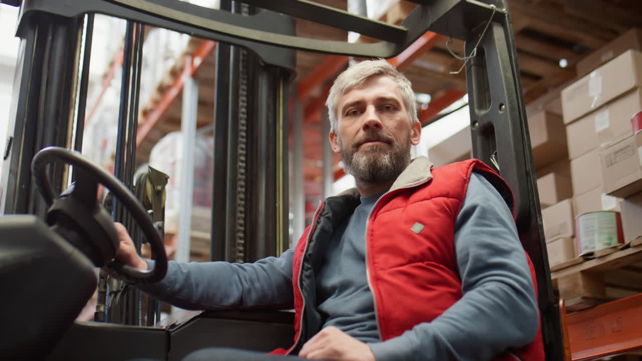 A mature man operating a forklift in a warehouse.