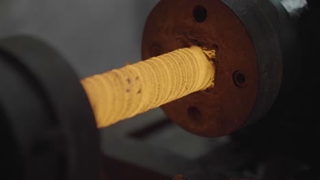 closeup of forging metal on a lathe during manufacturing process