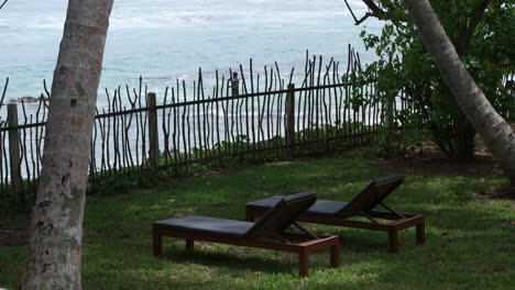 two lounge chairs under palm trees facing the ocean at resort in sri lanka