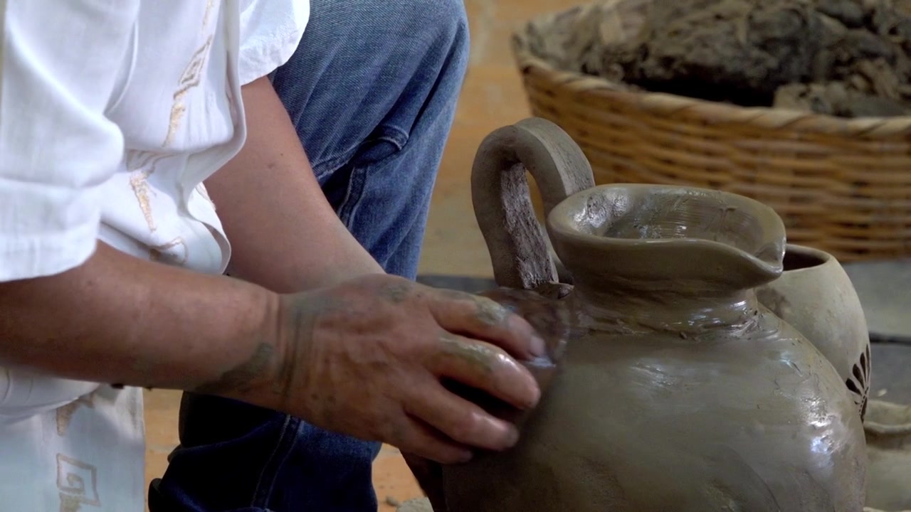 Primo piano di un artigiano che modella a mano argilla umida per ceramica all'interno di un laboratorio di ceramica tradizionale durante il processo di lavorazione artigianale della ceramica in Messico.