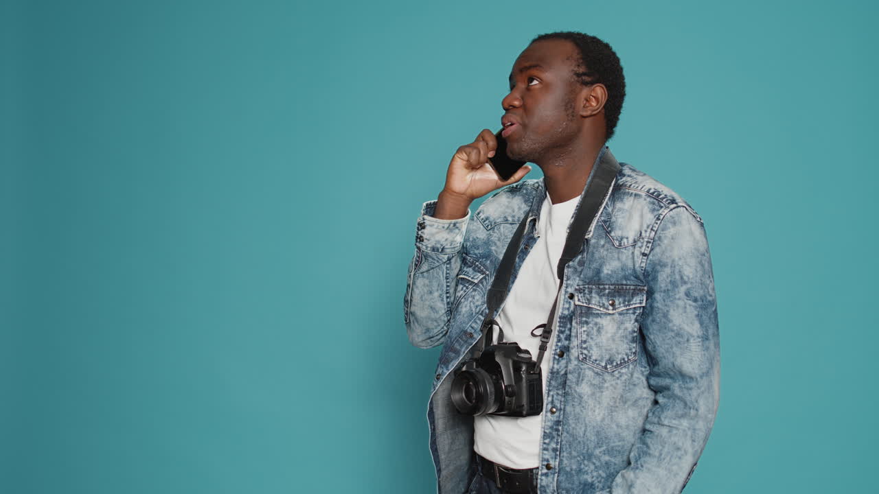 Young photographer talking on mobile phone call