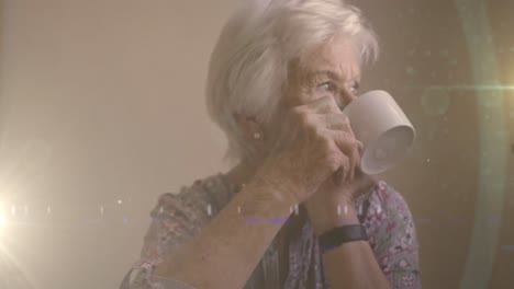 animation of glowing light over serious senior woman drinking tea