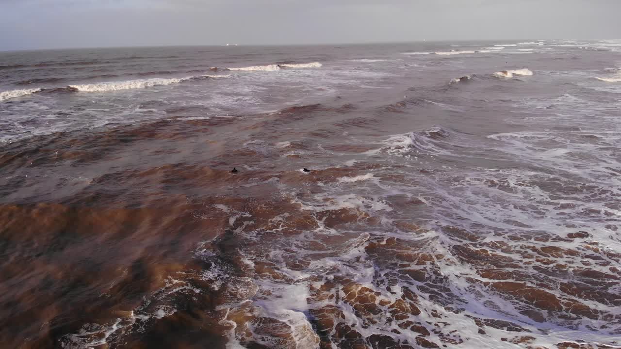 dos surfistas nadando a través del mar agitado en katwijk aan zee - toma aérea