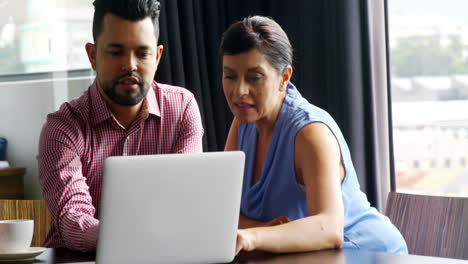 Business-executives-discussing-over-laptop