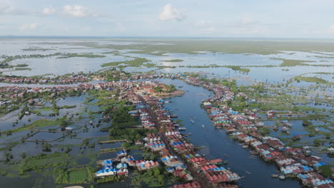 aerial video of tonlé sap floating village with waterways, blue rooftops, and green patches across vast wetlands