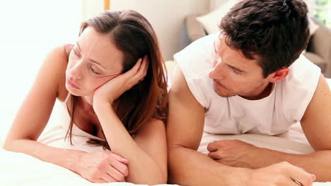 unhappy couple lying on bed not talking