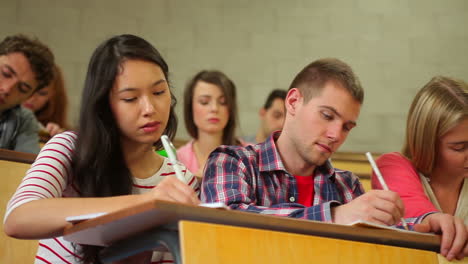 students listening in lecture hall and taking notes