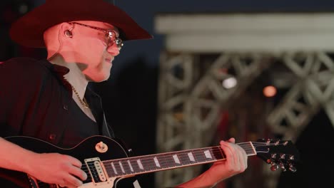 Male-musician-with-cowboy-hat-plays-black-electric-guitar-on-stage