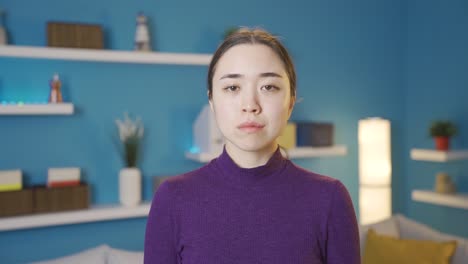 우울한 젊은 아시아 여성이 불행하고 슬픈 느낌으로 카메라를 쳐다보고 있습니다.