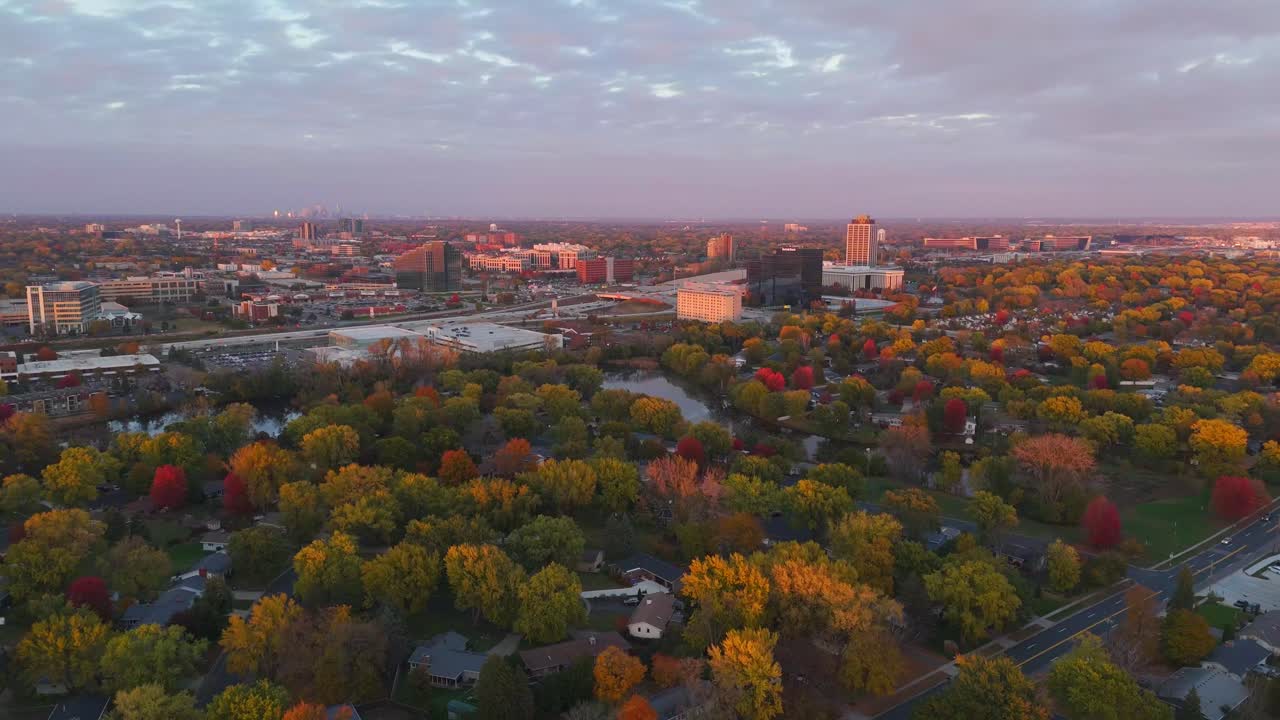 Una puesta de sol proyecta una luz cálida sobre una carretera en Bloomington, Minnesota, con follaje otoñal.