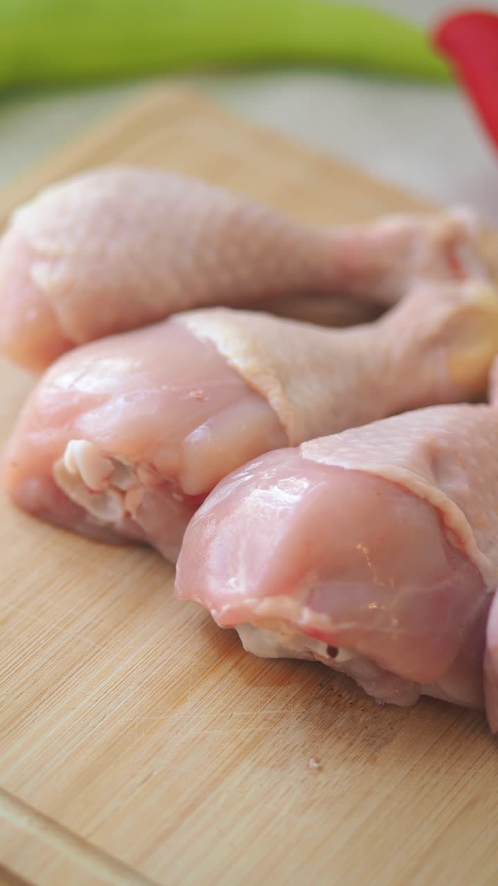 Fusi di pollo crudi su un tagliere di legno