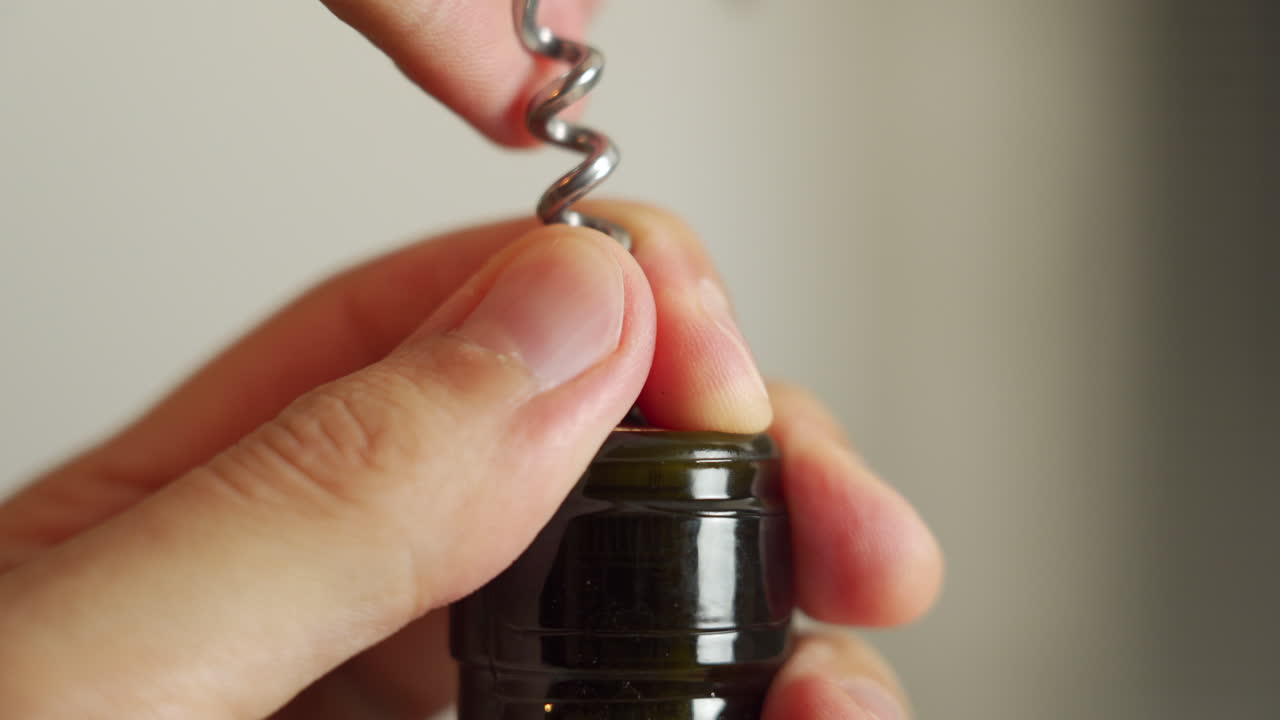 Grande plano de uma garrafa de vinho tinto sendo aberta com um saca-rolhas