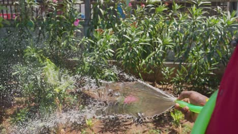 Primer-Plano-De-Una-Persona-Regando-Plantas-En-El-Jardín-Con-Una-Manguera-En-Mumbai,-India-1