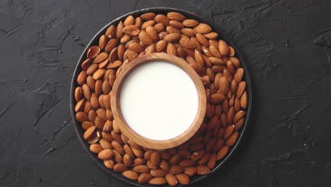 composition of almonds seeds and milk  placed on black stone background