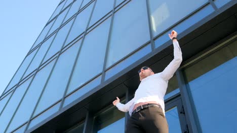an office worker spreads his hands against the background of a glass skyscraper a sense of freedom an office worker spreads his hands against the background of a glass skyscraper a sense of freedom business people