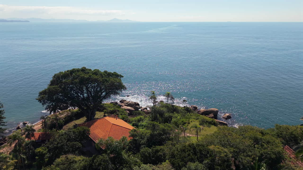 Drone fly above secluded beach house in a Brazilian tropical seafront landscape in Praia das Laranjeiras, Santa Catarina
