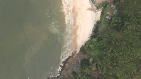 Descending-aerial-top-view-of-sandy-beach-in-Gokarna-beside-scenic-forest-in-summer,India