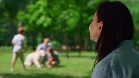 Dreamy-woman-sitting-in-front-of-playing-family-closeup.-Active-leisure-concept.