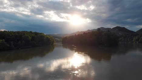 fast flight towards epic sunset with sunrays over river drau near maribor slowenia with forests in the background