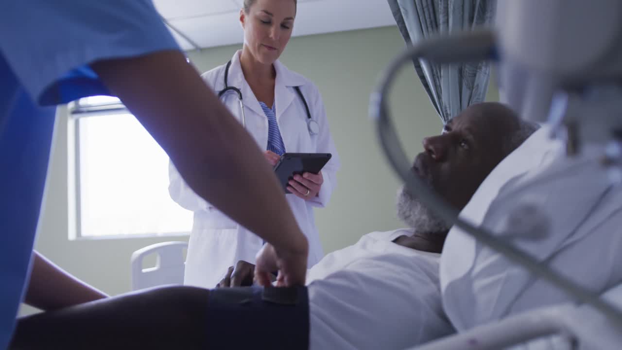 Diverse female doctor talking to male patient in hospital bed