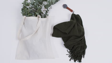 video de una bolsa de lona blanca con planta, bufanda, reloj, espacio de copia sobre un fondo blanco