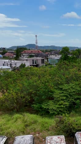 las imágenes de drones capturan un estacionamiento de autobuses desierto en phuket, tailandia, con vehículos oxidados y vegetación cubierta bajo cielos despejados.