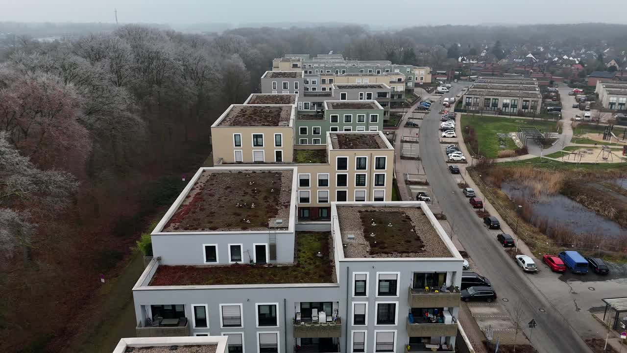 Different colored residential apartment with green rooftop garden in new developed housing area of USA. Aerial top down flyover shot. Cloudy and frosty winter day in Germany. Wide shot.
