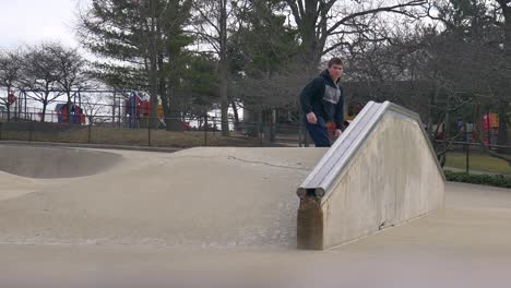 man does a rail slide at the skatepark