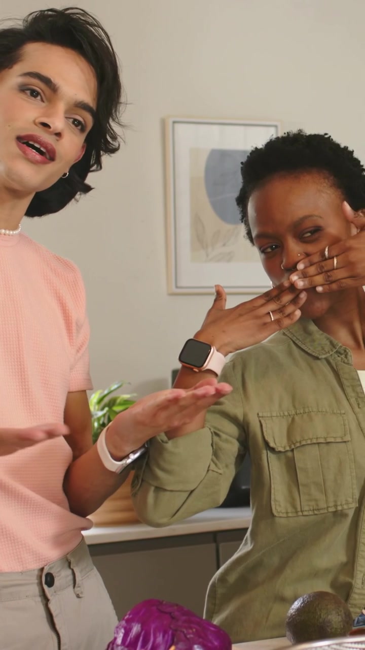 Vertical video: Performing host in pink shirt after cue, gesturing for kitchen demo with cabbage