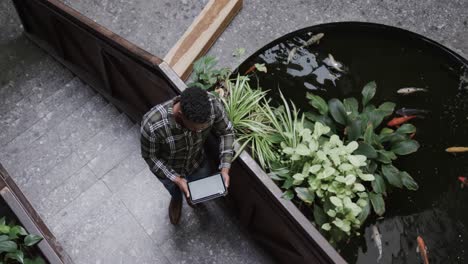 High-angle-view-of-african-american-male-designer-using-tablet-in-casual-office,-slow-motion