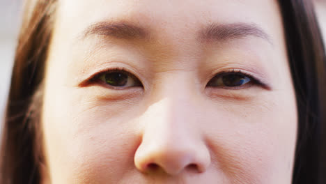 Video-of-close-up-of-portrait-of-happy-asian-woman-posing-in-garden