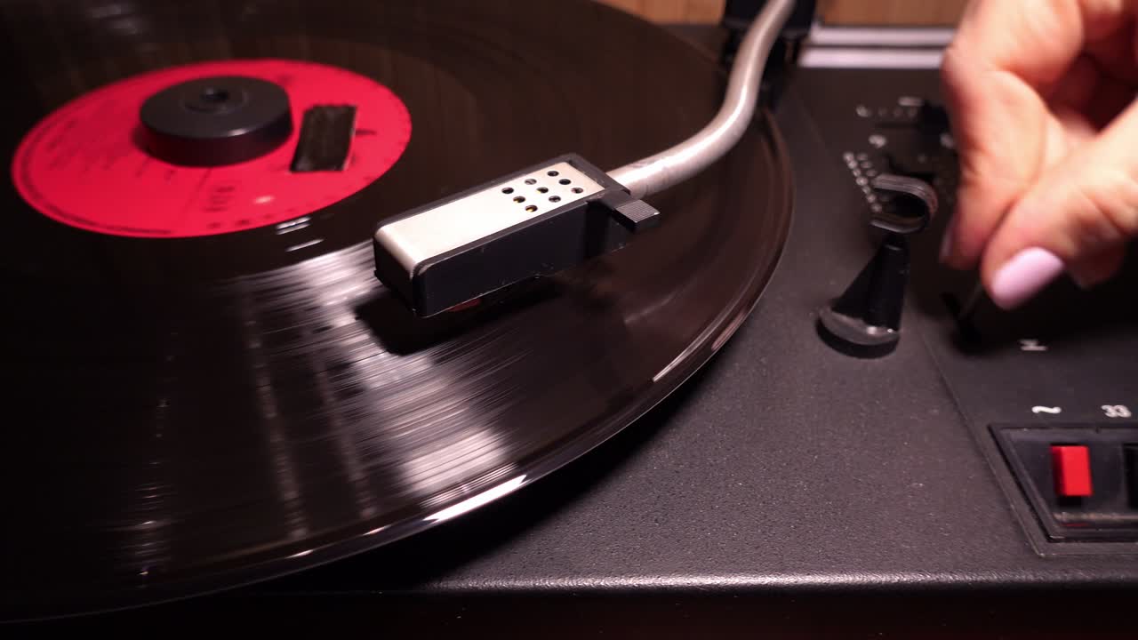 여성은 80 년대 정적 클로즈업에서 레트로 바늘 그라모폰에서 비닐 레코드를 재생합니다.