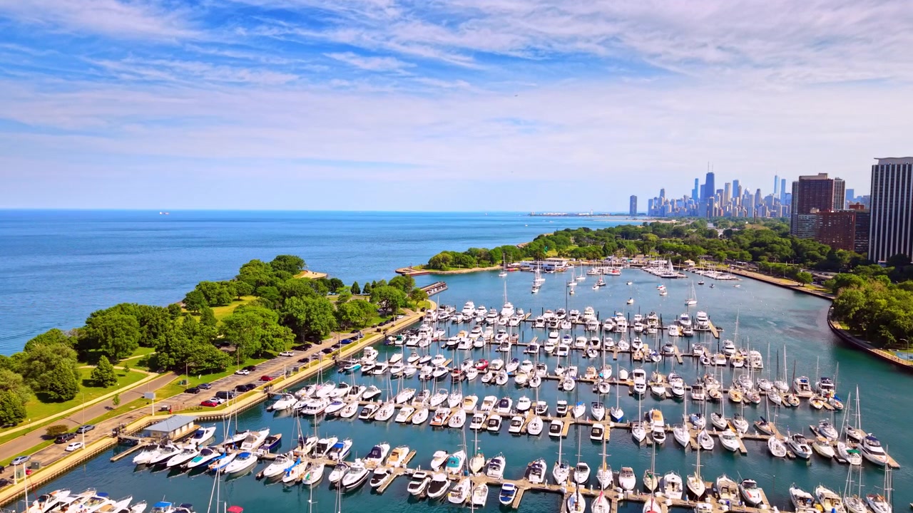 Rows of docked boats along Lake Michigan marina, Chicago, Illinois. Wide aerial view shows a full harbor beside green shoreline park, with the downtown skyline visible on the horizon.