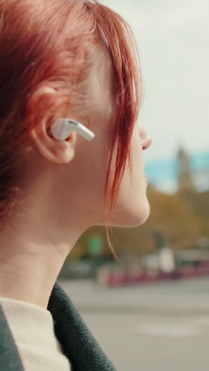 Giovane donna che ascolta la musica con auricolari wireless in città
