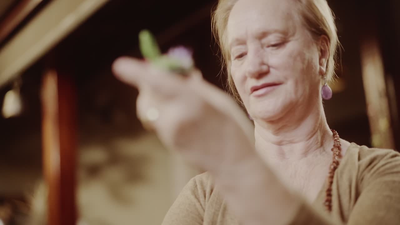 Elderly woman examining a small plant or craft object